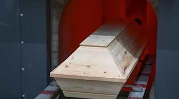 Ein Sarg wird in den Ofen des Krematorium zur Einäscherung hineingefahren. Foto: Felix Kästle/dpa