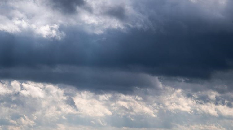 Dunkle Wolken ziehen über Windrädern hinweg. Foto: Julian Stratenschulte/dpa