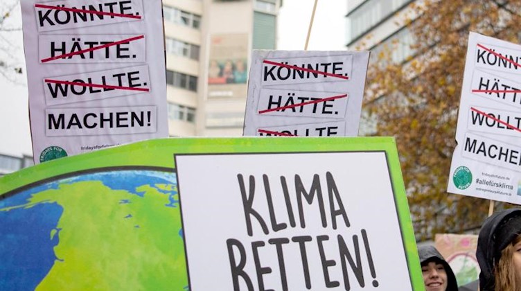 Demonstranten von Fridays for Future halten Plakate mit der Aufschrift «Klima Retten!» und «Könnte. Hätte. Wollte. Machen!» in die Luft. Foto: Tom Weller/dpa/Symbolbild