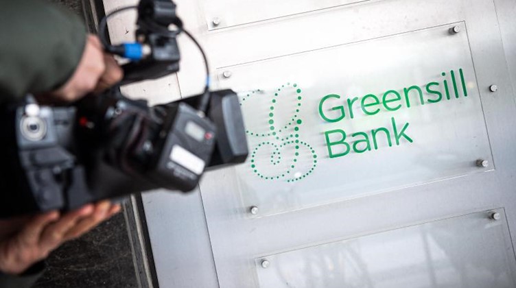 Ein Schild mit dem Firmennamen «Greensill Bank» wird von einem Fernsehteam gefilmt. Foto: Sina Schuldt/dpa/Archivbild