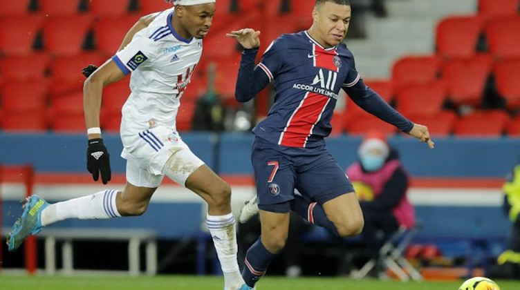 Straßburgs Mohamed Simakan (l) sprintet mit Kylian Mbappe von Paris Saint-Germain dem Ball hinterher. Foto: Christophe Ena/AP/dpa/Archivbild