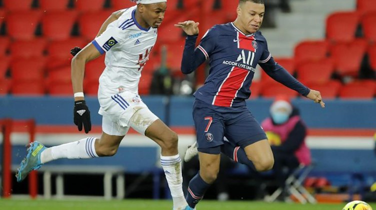 Straßburgs Mohamed Simakan sprintet mit Kylian Mbappe von Paris Saint-Germain dem Ball hinterher. Foto: Christophe Ena/AP/dpa