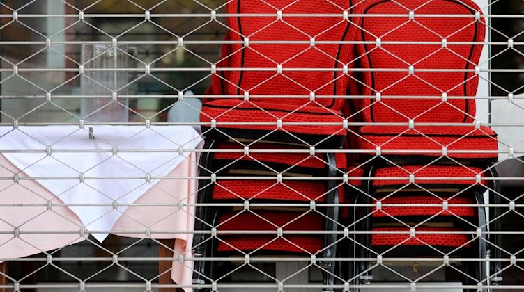 Hinter einem Gitter eines geschlossenen Restaurants stehen Stühle. Foto: Oliver Berg/dpa/Symbolbild