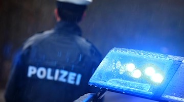 Ein Polizist steht vor einem Streifenwagen. Foto: Karl-Josef Hildenbrand/dpa/Symbolbild