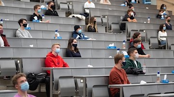 Studierende mit Mund- und Nasenmaske sitzen im Vorlesungssaal. Foto: Sebastian Gollnow/dpa/Symbolbild