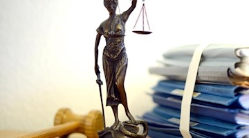 Eine Figur der Justitia steht neben einem Holzhammer und einem Aktenstapel. Foto: Volker Hartmann/dpa/Symbolbild
