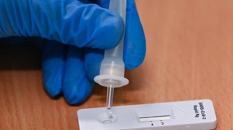 Eine Mitarbeiterin vom Gesundheitsamt tropft eine Flüssigkeit auf einen Corona-Schnelltest. Foto: Patrick Pleul/dpa-Zentralbild/dpa/Symbolbild