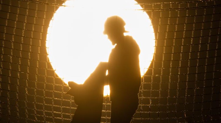 Ein Bauarbeiter steht bei Sonnenaufgang auf einer Baustelle. Foto: Julian Stratenschulte/dpa/Symbolbild