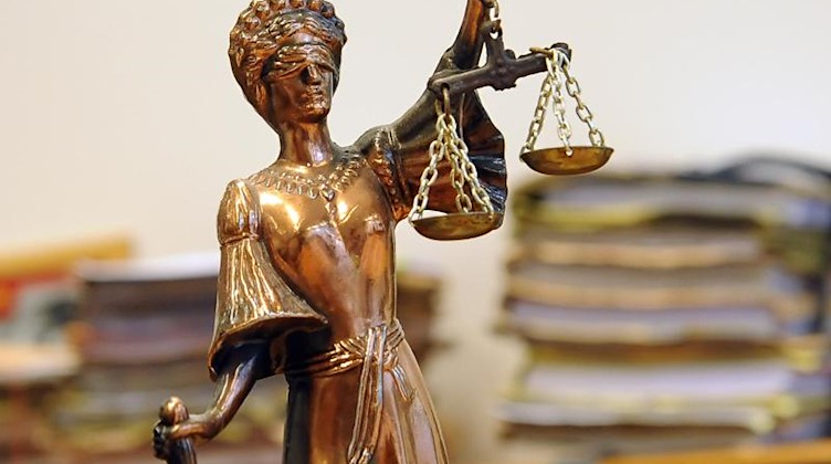 Eine goldfarbene Justitia-Figur steht vor Aktenbergen, die sich auf einem Tisch stapeln. Foto: Britta Pedersen/dpa-Zentralbild/dpa/Symbolbild