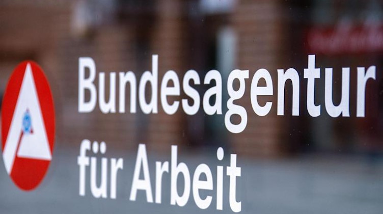 Das Hinweisschild für die Bundesagentur für Arbeit ist an einer Glasfläche vor einem Bürogebäude zu sehen. Foto: Jens Büttner/dpa-Zentralbild/dpa/Symbolbild