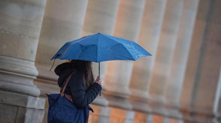 Eine Passantin geht bei Regen durch die Stadt. Foto: Marijan Murat/dpa/Symbolbild