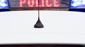 "Police" steht auf dem Display eines Polizeiwagens mit angeschaltetem Blaulicht. Foto: Friso Gentsch/dpa/Archivbild