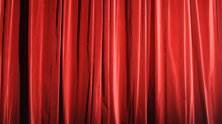 Ein roter Vorhang einer Theaterbühne ist zu sehen. Foto: Marcus Brandt/dpa/Symbolbild