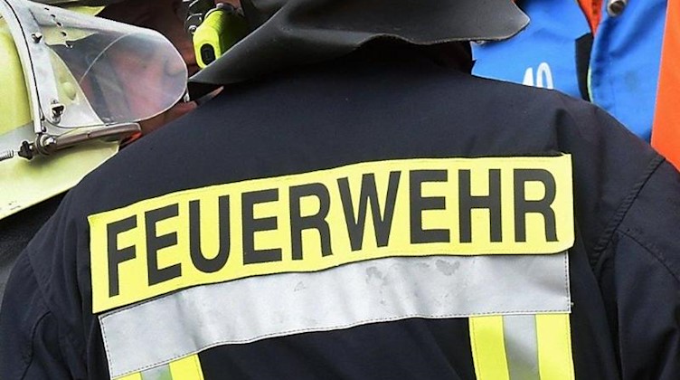 Der Schriftzug Feuerwehr steht an der Jacke eines Feuerwehrmannes. Foto: picture alliance / dpa/Symbolbild