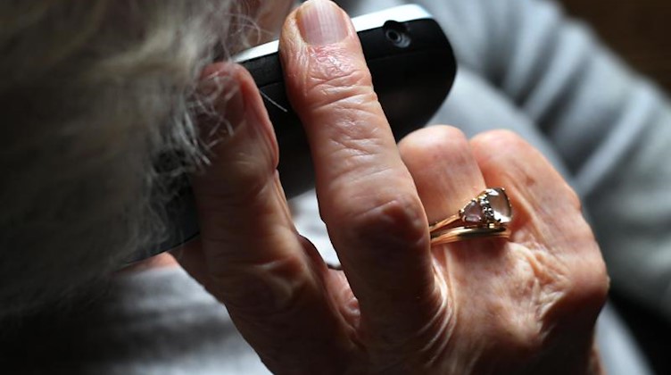 Eine Rentnerin hält ein Telefon in der Hand. Foto: Karl-Josef Hildenbrand/dpa/Symbolbild