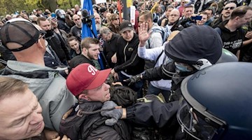 Polizisten halten Teilnehmer einer Demo gegen Corona-Schutzmaßnahmen zurück. Foto: Fabian Sommer/dpa/Symbolbild