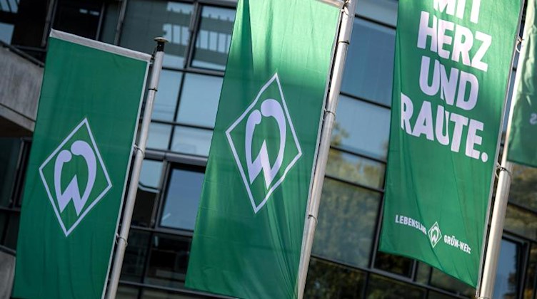 Flaggen mit dem Logo von Werder Bremen wehen im Wind. Foto: Sina Schuldt/dpa/Archivbild