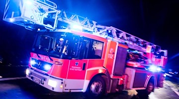Ein Drehleiterwagen der Feuerwehr fährt mit Blaulicht an einer Unfallstelle vorbei. Foto: Marcel Kusch/dpa/Illustration