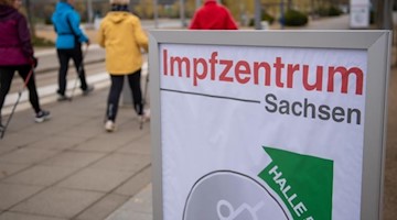 Ein Plakat mit der Aufschrift Impfzentrum Sachsen weist den Weg für Fußgänger. Foto: Hendrik Schmidt/dpa-Zentralbild/ZB/Symbolbild