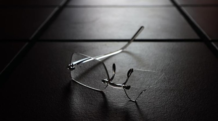 Eine zerbrochene Brille liegt auf dem Boden. Foto: Karl-Josef Hildenbrand/dpa/Symbolbild