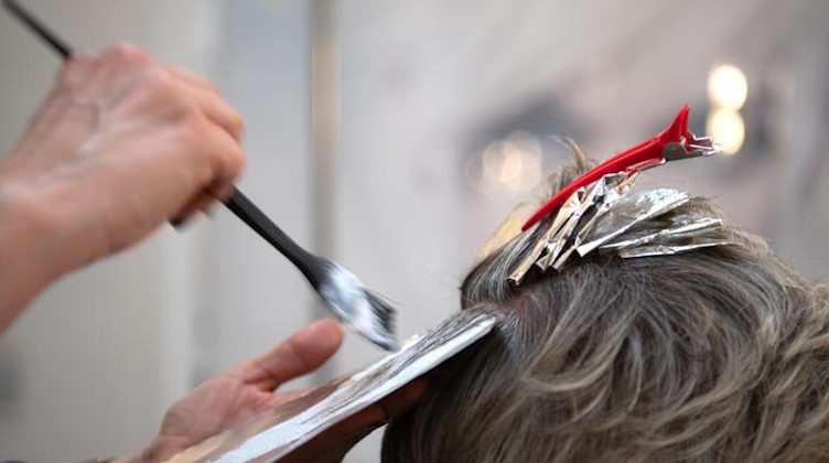 Eine Friseurin färbt einer Kundin mit einem Pinsel die Haare in einem Friseur-Salon. Foto: Symbolbild Friseur/dpa/Symbolbild