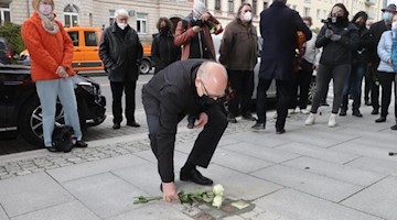 Sven Schulze (SPD), Oberbürgermeister von Chemnitz, legt Blumen nach der Verlegung von Stolpersteinen auf dem Gehweg der Zschopauer Straße nieder. Foto: Bodo Schackow/dpa-Zentralbild/dpa