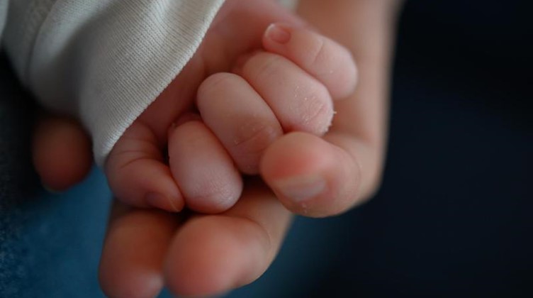 Die Hand eines zwei Wochen altes Neugeborenen liegt in der Hand seiner Mutter. Foto: Sebastian Gollnow/dpa/Symbolbild