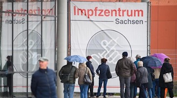 Menschen warten vor dem Impfzentrum an der Messe Dresden. Foto: Robert Michael/dpa-Zentralbild/dpa/Archivbild