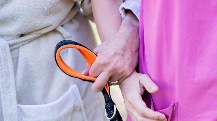 Eine Pflegekraft geht mit einer Patientin spazieren. Foto: Christoph Soeder/dpa/Symbolbild