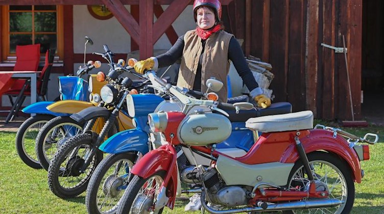 Silke Gute steht zwischen verschieden Mopeds aus DDR-Zeiten. Foto: Patrick Pleul/dpa-Zentralbild/dpa