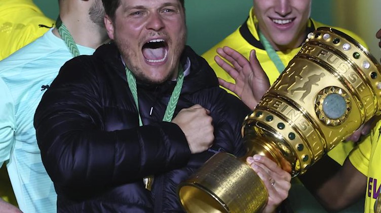 Edin Terzic (M), Dortmunds Cheftrainer, hält den Pokal im Arm. Foto: Martin Rose/POOL Getty/AP/dpa