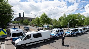 Polizeifahrzeuge stehen vor dem Stadion. Foto: Sebastian Kahnert/dpa/aktuell