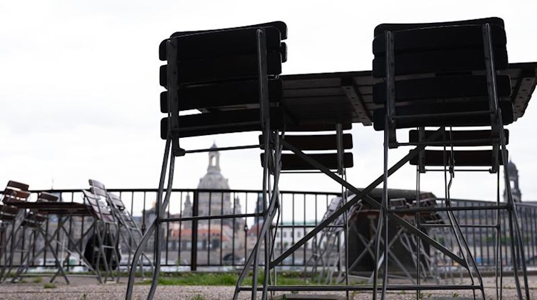 Tische und Stühle sind in einem Biergarten vor der Kulisse der Frauenkirche zusammengestellt. Foto: Sebastian Kahnert/dpa-Zentralbild/dpa