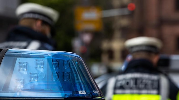 Polizeibeamte stehen zwischen zwei Einsatzfahrzeugen der Polizei. Foto: Philipp von Ditfurth/dpa/Symbol