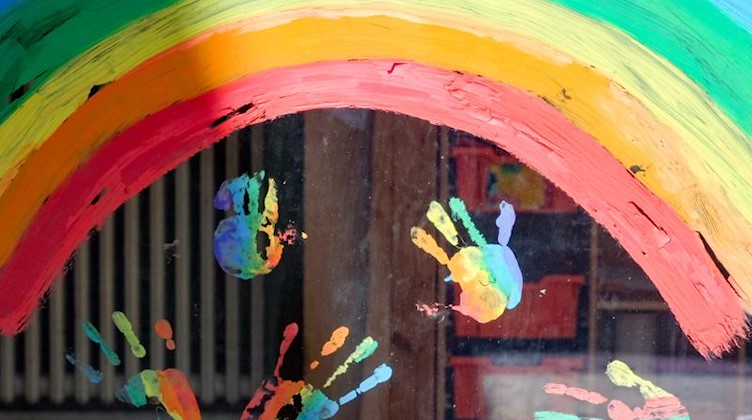 Kinderhände und ein Regenbogen sind an einer Kita zu sehen. Foto: Jens Kalaene/dpa-Zentralbild/dpa/Symbolbild/Archivbild