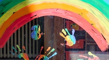 Kinderhände und ein Regenbogen sind an einer Kita zu sehen. Foto: Jens Kalaene/dpa-Zentralbild/dpa/Symbolbild/Archivbild