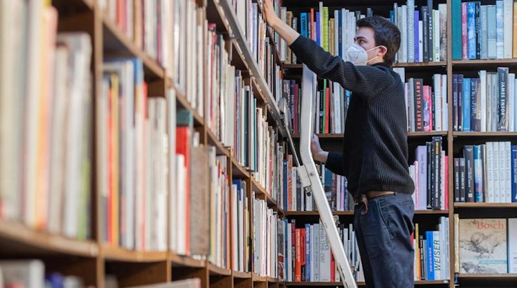 Ein Mitarbeiter steht auf einer Leiter in einer Buchhandlung. Foto: Rolf Vennenbernd/dpa/Symbolbild