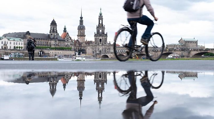 Ein Radfahrer fährt am Ufer Elbe vor der Kulisse der Altstadt entlang durch Pfützen. Foto: Sebastian Kahnert/dpa-Zentralbild/dpa/Archivbild
