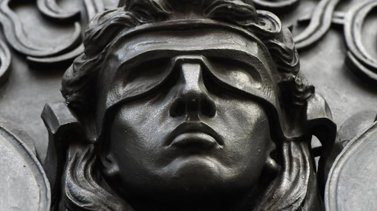 Ein Relief, das das Haupt der Justita mit verbundenen Augen darstellt, ist an einem Gerichtsgebäude angebracht. Foto: Sonja Wurtscheid/dpa/Symbolbild