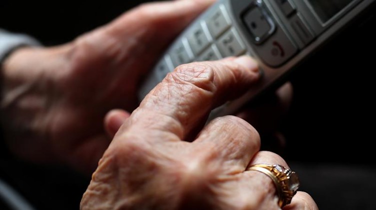 Eine ältere Frau tippt auf einem schnurlosen Festnetztelefon. Foto: Karl-Josef Hildenbrand/dpa/Illustration