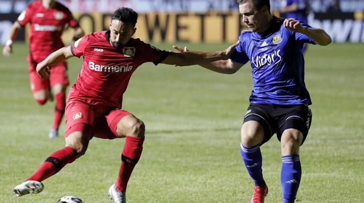 Fußballspieler Karim Bellarabi (l) in Aktion gegen Anthony Barylla. Foto: Ronald Wittek/epa-Pool/dpa/Archivbild