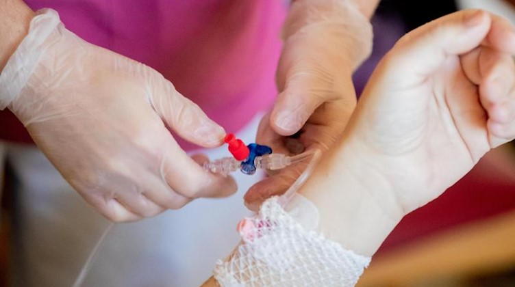Eine Krankenpflegerin schließt bei einem Patientenrundgang eine Infusion an. Foto: Christoph Soeder/dpa/Archivbild