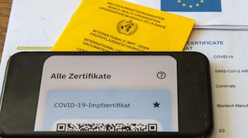Ein Impfpass und ein Smartphone, auf dem die App CovPass läuft. Foto: Stefan Puchner/dpa