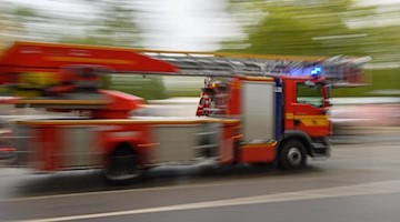 Ein Feuerwehrfahrzeug mit Drehleiter fährt zu einem Einsatz. Foto: Robert Michael/dpa-Zentralbild/ZB/Symbolbild