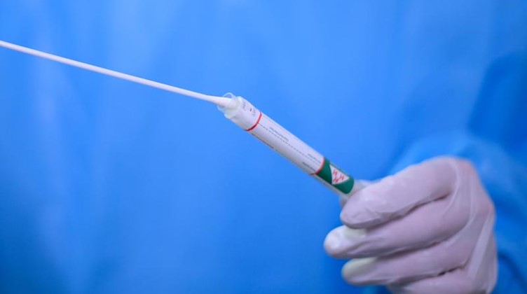 Ein Arzt gibt einen Tupfer mit einem Abstrich für einen Corona-Test in ein Teströhrchen. Foto: Robert Michael/dpa-Zentralbild/dpa/Symbolbild