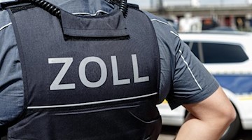 Ein Beamter trägt während seines Dienstes eine Schutzweste mit der Rückenaufschrift "Zoll". Foto: Markus Scholz/dpa/Symbolbild