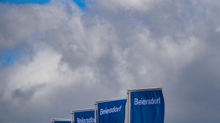 Fahnen der Beiersdorf AG wehen während der Hauptversammlung. Foto: Axel Heimken/dpa/Archivbild