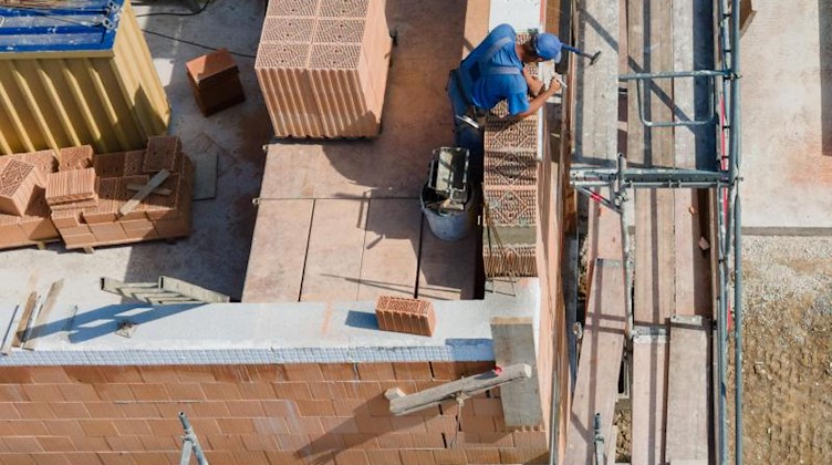Ein Bauarbeiter steht auf einer Baustelle und mauert eine Wand. Foto: Tom Weller/dpa/Symbolbild