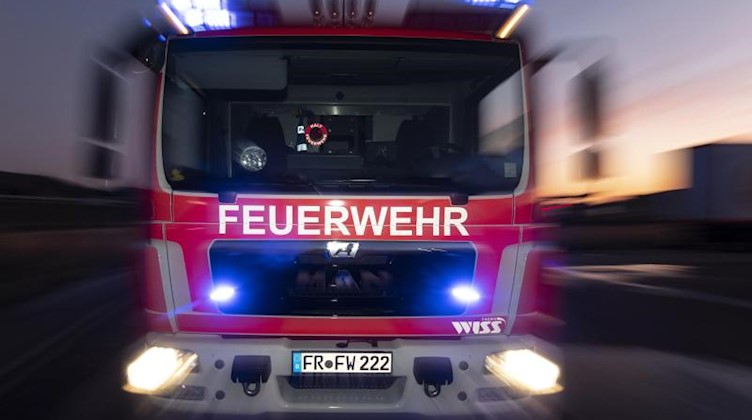 Ein Feuerwehrfahrzeug steht mit eingeschaltetem Blaulicht auf einer Straße. Foto: Patrick Seeger/dpa/Symbolbild