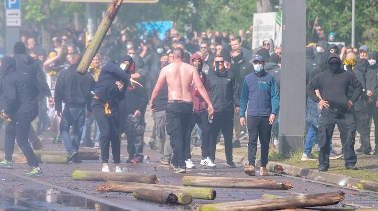 Fans von Dynamo Dresden werfen Holzpfähle in Richtung der Polizei. Foto: Sebastian Kahnert/dpa/Archivbild